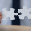 Businessman's hands putting two jigsaw pieces together