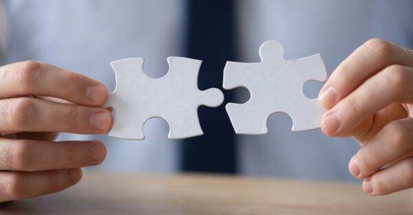 Businessman's hands putting two jigsaw pieces together